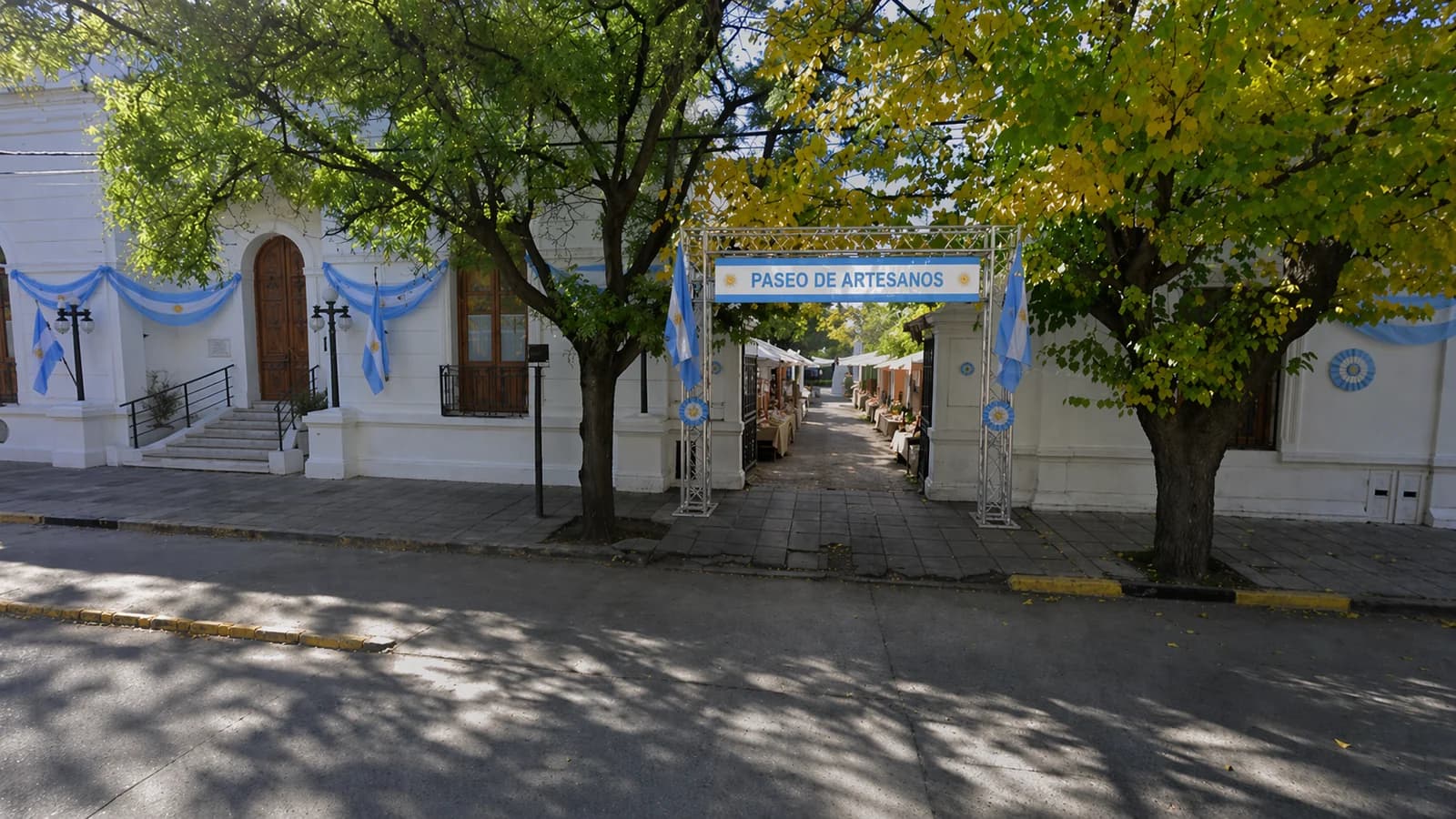 Paseo de Artesanos en el Patio del Palacio Municipal · entrada con banderas y escarapelas